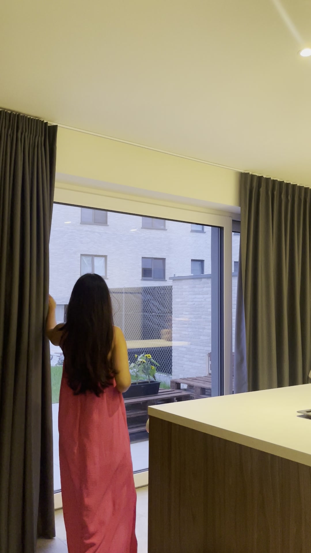 Woman closes dark curtains indoors